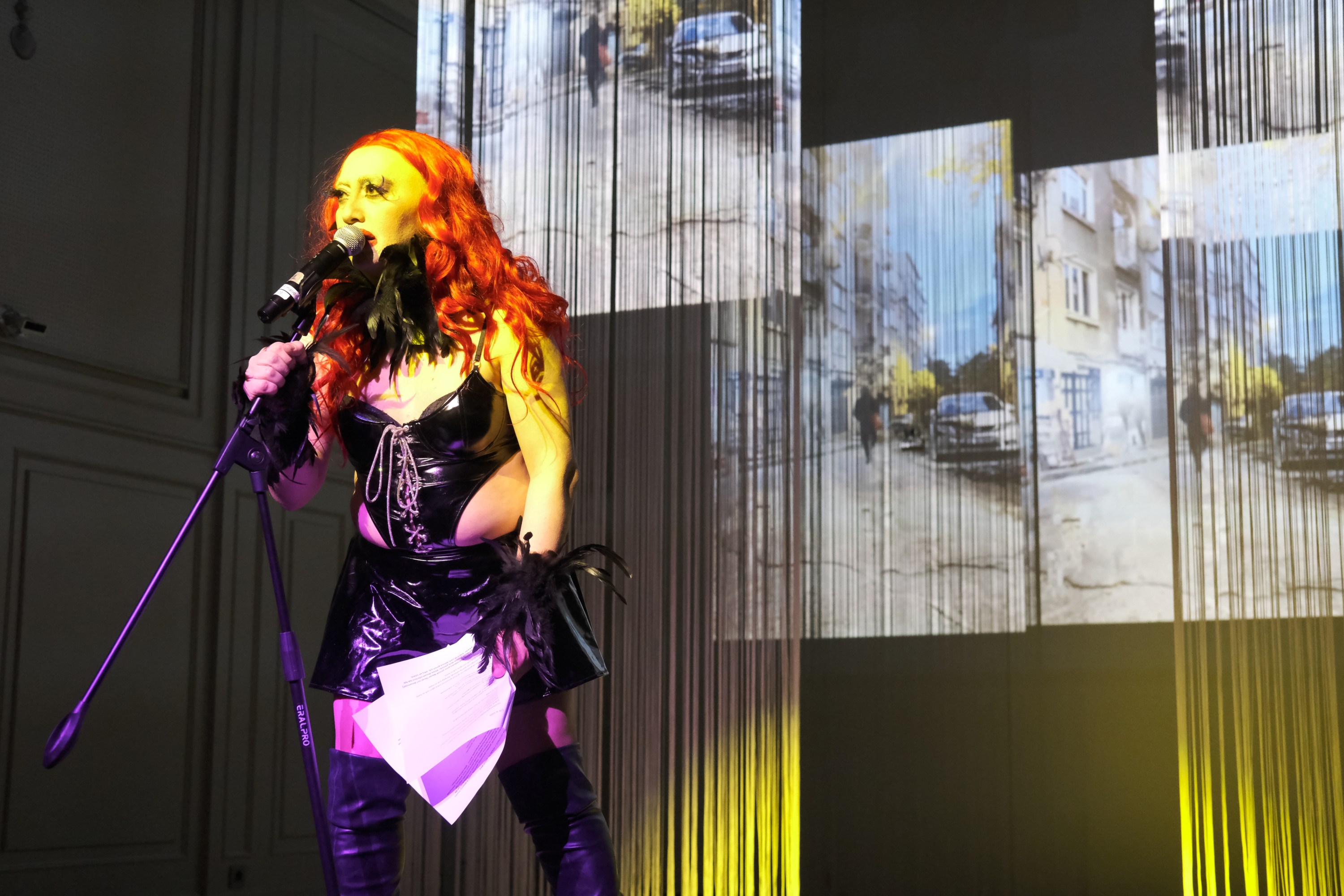 View of Jilet Sebahat on stage holding a microphone stand during a performance of Above the Clouds, Underground at Koma Sahnesi.