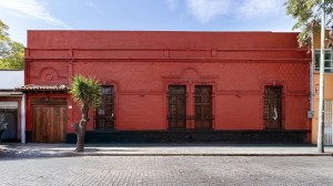 A rectangular, red building on a brick road.