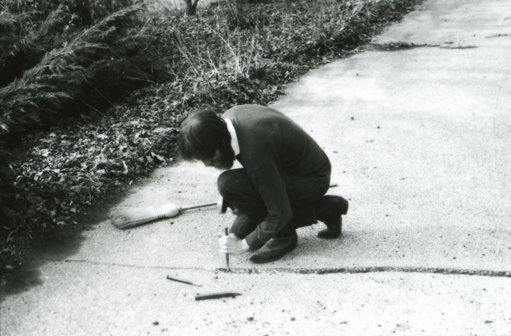 Lawrence Weiner constructing his 1968 A 2" WIDE 1" DEEP TRENCH CUT ACROSS A STANDARD ONE-CAR DRIVEWAY, Mamaroneck, NY, 1968. © Lawrence Weiner Estate/Artists Rights Society (ARS), New York.