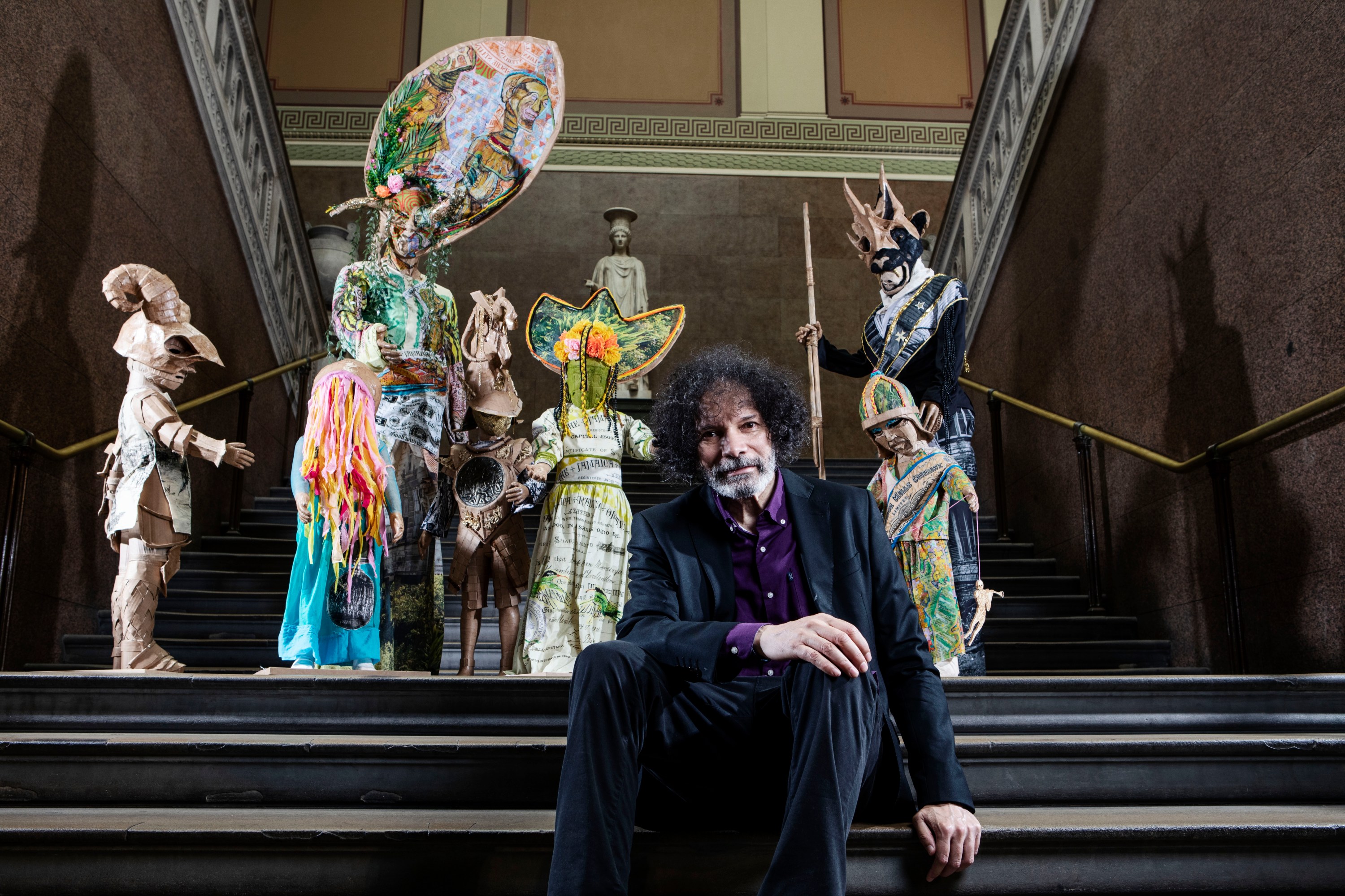 Artist Hew Locke poses beside his sculptural installation, The Watchers.