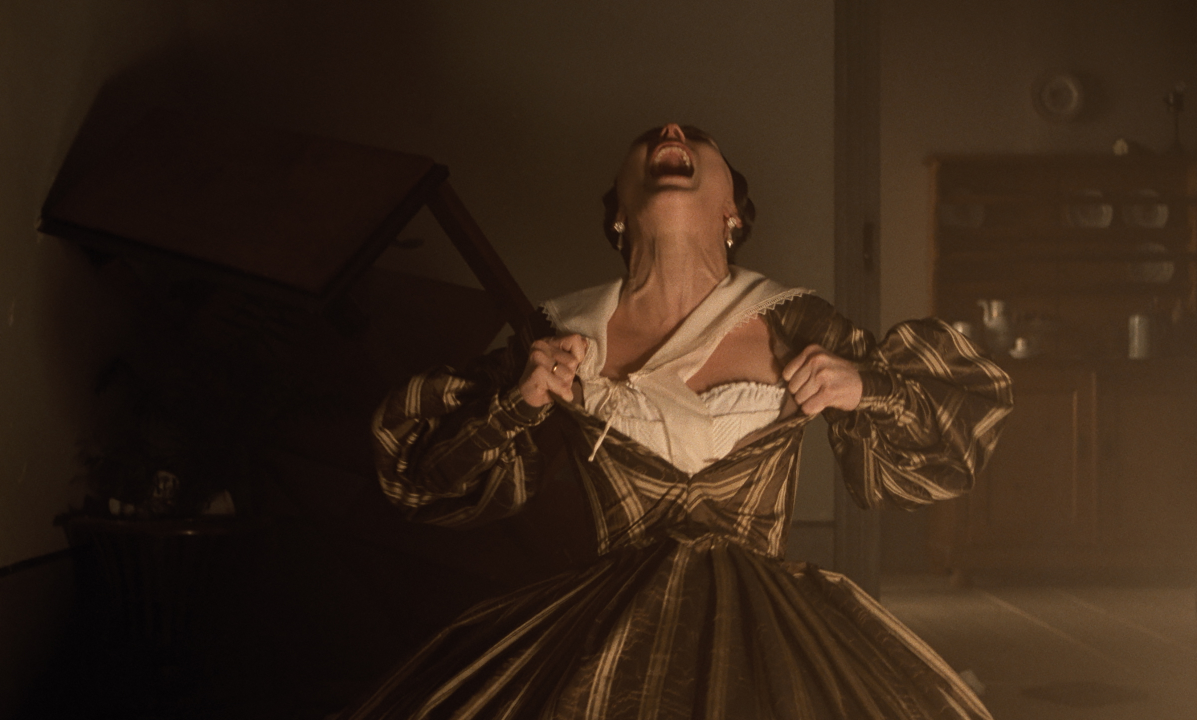 Actress Lily-Rose Depp with her head thrown back in a primal yell as she rips open the front of her dress in a still from Robert Eggers's Nosferatu.