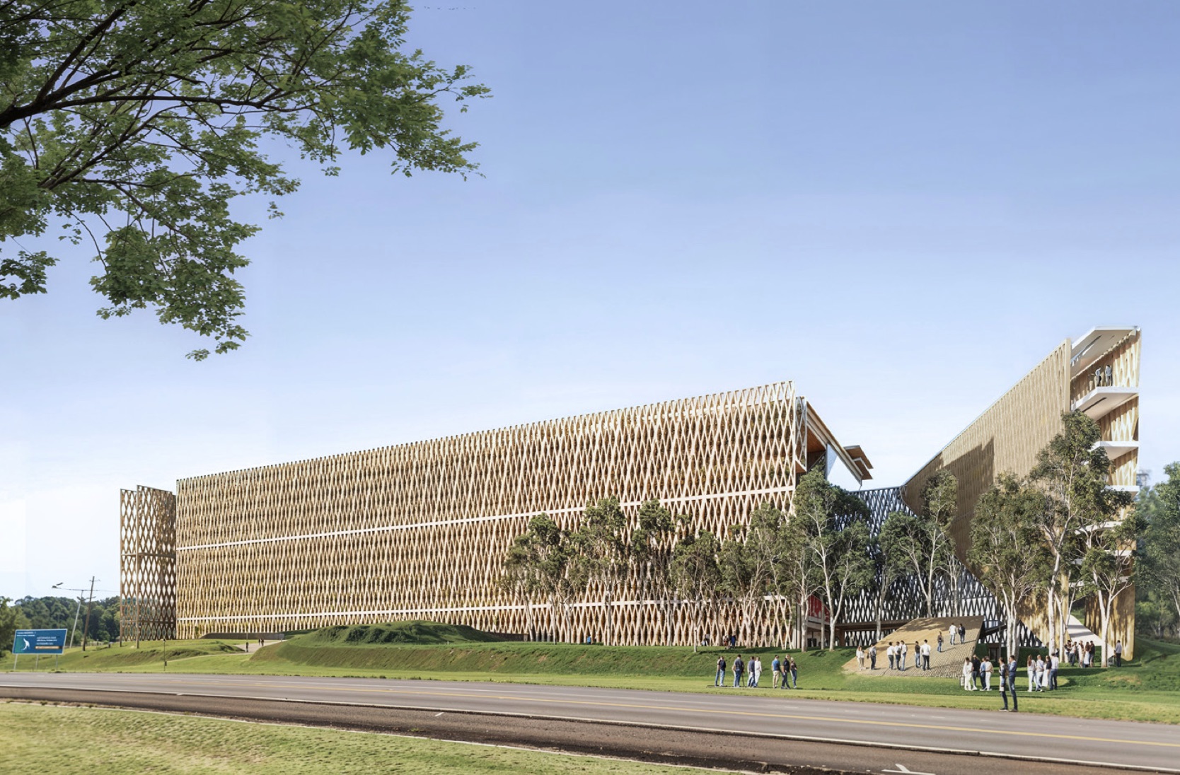 A modern building with a unique, lattice-like design surrounded by trees and grass. A road and open park space are visible in the foreground, with people walking nearby. The sky is clear and blue.