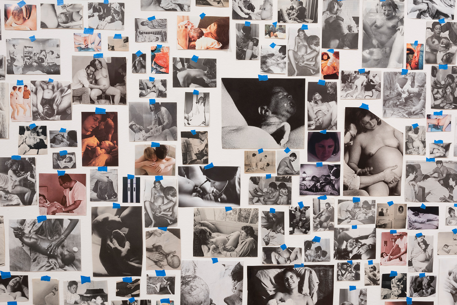 A collage of vintage and contemporary photos showing childbirth, pregnancy, and infant care, arranged on a wall with blue tape. Carmen Winant, My Birth (detail), 2018, 3,059 found paper and photographic prints, painter’s tape, dimensions variable.